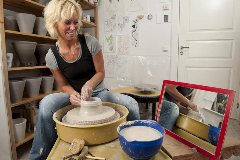 西方人,一个人,坐,笑,微笑,露齿笑,横图,室内,白天,正面,绘画,镜子,门,花盆,欧洲,欧洲人,仅一个年轻女性,仅一个女性,仅一个人,一面,一排,许多,服装,朦胧,模糊,整齐,木制,彩绘,瓷器,陶瓷,墙,置物架,注视,休闲装,架子,墙壁,墙面,排列,衣服,黄色,蓝色,白色,黑色,木制品,容器,门框,观察,看,休闲,休闲服,金色,服饰,观看,储藏,镜像,察看,陶艺,镜面,储存,队列,关注,陈列架,彩釉,搁架,拉坯,年轻女性,女人,女性,白种人,长发,画画,坐着,半身,彩图,贮存