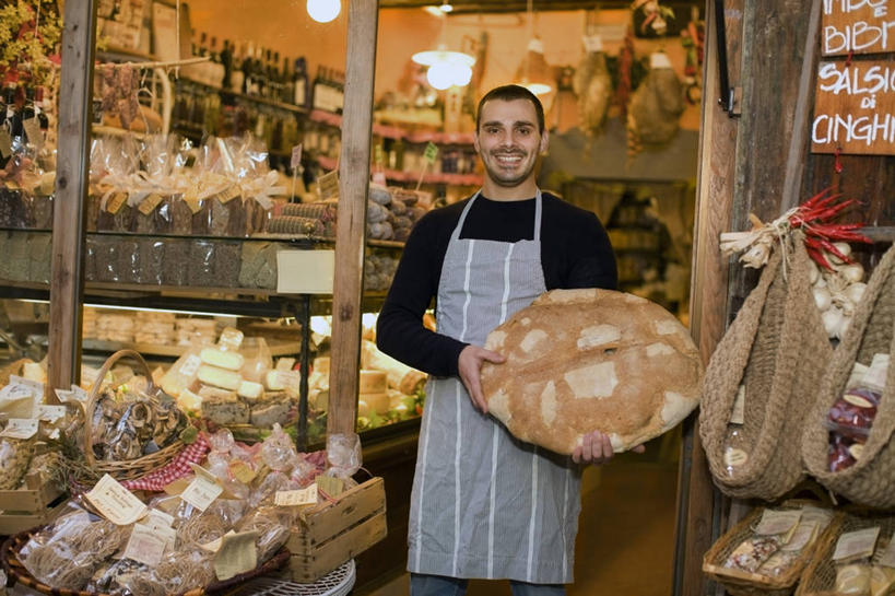 点心,面包,西方人,一个人,店员,商店,站,捧,笑,微笑,露齿笑,横图,室外,白天,正面,窗户,落地窗,桌子,橱窗,袋子,照明,欧洲,欧洲人,仅一个男性,仅一个人,一堆,许多,阴影,堆叠,堆积,服装,光线,木制,英文,标志,围裙,文字,影子,字符,字母,灯光,食品,面点,麻袋,茶几,注视,休闲装,标识,商铺,顶灯,货架,玻璃窗,架子,灯,食物,糕点,排列,仅一个年轻男性,两个,衣服,木制品,容器,灯具,观察,看,站着,营业员,休闲,休闲服,服饰,观看,储藏,堆,英文字母,照亮,察看,照明设备,储存,队列,关注,陈列架,玻璃橱窗,市肆,商号,销售人员,男人,男性,年轻男性,白种人,售货员,端,端着,捧着,手捧,站立,半身,彩图,店铺,熟食店,贮存