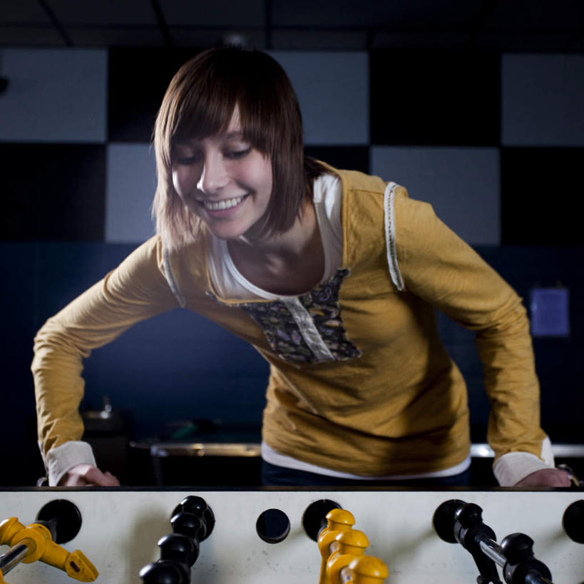 西方人,一个人,站,笑,微笑,露齿笑,方图,室内,白天,正面,锻炼,游戏,运动,足球,欧洲,欧洲人,仅一个年轻女性,仅一个女性,仅一个人,弯腰,阴影,服装,光线,影子,灯光,玩,注视,休闲装,娱乐,衣服,观察,看,站着,休闲,休闲服,服饰,观看,活动,察看,发泄,关注,消遣,智力,桌式足球,桌上足球,宣泄,弯身,体育,年轻女性,女人,女性,白种人,玩耍,嬉戏,站立,半身,彩图,健身