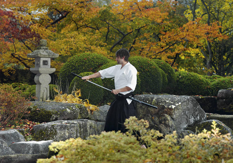 西方人,一个人,站,横图,室外,白天,正面,民族服装,竞争,石头,植物,照明,欧洲,欧洲人,仅一个男性,仅一个人,对抗,握,服装,冲突,灯笼,石子,武士刀,刀具,拿,拿着,注视,破坏,树,树木,仅一个年轻男性,衣服,绿色,自然,灯具,刀,观察,看,站着,武器,战争,握着,服饰,生长,成长,观看,照亮,损坏,察看,攻击,威胁,衣着,照明设备,穿着,对立,关注,矛盾,兵器,防御,日本刀,敌对,挫败,斗争,抗拒,抗衡,冷兵器,凶器,杀伤,威慑,东洋刀,东瀛刀,日本武士刀,衣饰,危险,男人,男性,年轻男性,白种人,石块,站立,半身,彩图,传统服装,民俗服,石灯笼