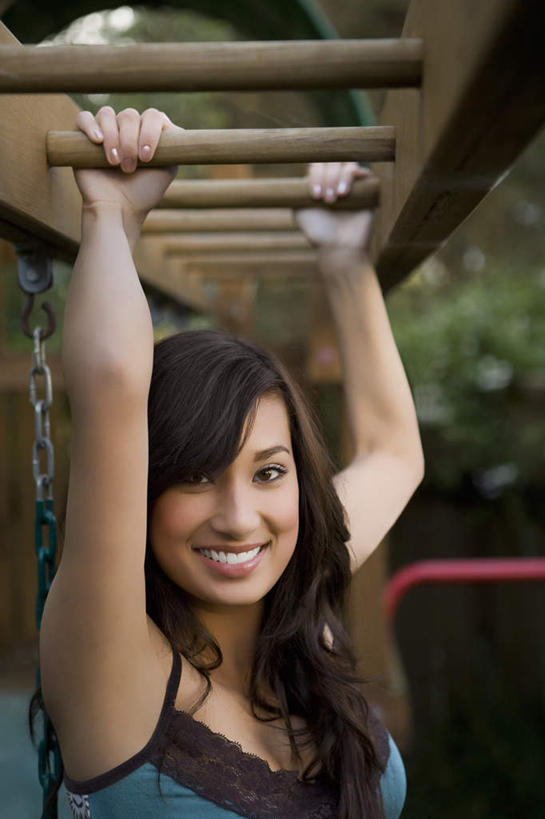 一个人,举,笑,微笑,露齿笑,竖图,室外,白天,正面,游戏,植物,玩具,吊带,亚洲,仅一个年轻女性,仅一个女性,仅一个人,服装,朦胧,模糊,玩,注视,吊带衫,娱乐,架子,树,树木,衣服,绿色,黑色,自然,观察,看,托,休闲,益智,服饰,生长,成长,观看,活动,察看,衣着,攀登架,穿着,发泄,关注,消遣,智力,宣泄,衣饰,年轻女性,女人,女性,亚洲人,印度人,举起,举手,举着,玩耍,嬉戏,向上举,向上伸,向上托,半身,彩图,攀爬架