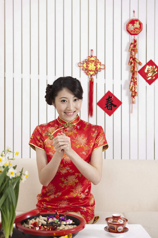 东方人,一个人,客厅,坐,笑,微笑,露齿笑,竖图,室内,白天,正面,民族服装,沙发,桌子,鞭炮,春节,对联,亚洲,仅一个年轻女性,仅一个女性,仅一个人,吊挂,悬挂,旗袍,服装,节日,庆祝,艺术,木制,标志,文字,字符,手工艺品,陶瓷,食品,糖,糖果,甜点,甜品,陶瓷制品,软糖,挂,茶几,注视,黄种人,文化,标识,食物,衣服,红色,木制品,容器,工艺品,碗,甜食,观察,看,庆典,汉字,服饰,观看,纪念,储藏,春联,察看,起居室,高雅,衣着,储存,穿着,关注,中国文化,中文,布艺沙发,自信心,品位,国文,华文,衣饰,客堂,年轻女性,女人,女性,亚洲人,爆竿,爆仗,爆竹,鞭爆,炮仗,坐着,半身,彩图,传统服装,民俗服,对子,楹联,拜年,贺年,贮存,传统文化