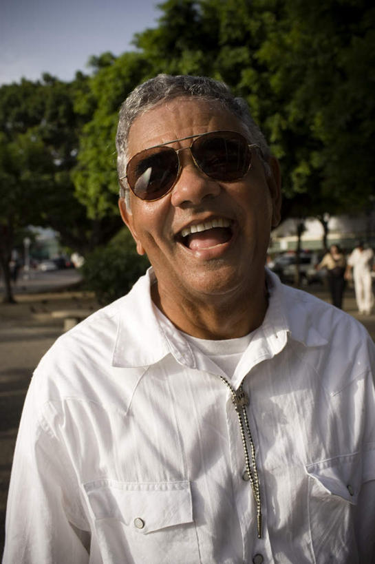 西方人,一个人,站,笑,大笑,竖图,室外,白天,正面,兴奋,植物,道路,路,汽车,项链,欧洲,非洲,黑人,欧洲人,仅一个男性,仅一个人,一副,墨镜,眼镜,小路,交通,车,装饰品,树,树木,蓝色,绿色,蓝天,天空,自然,饰品,首饰,太阳镜,太阳眼镜,交通工具,轿车,天,站着,张嘴,仅一个老年男性,遮阳镜,生长,成长,载具,张大嘴巴,哈哈大笑,老年男性,男人,男性,非洲人,张开嘴,站立,半身,彩图,高兴,狂笑