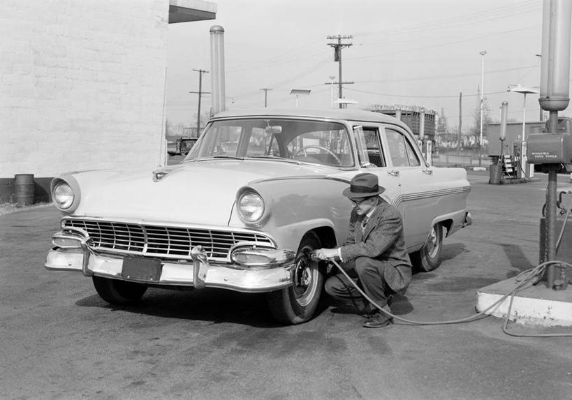 成年人,中年人,老年人,一个人,蹲,横图,黑白,室外,白天,帽子,美国,仅一个男性,仅一个人,仅一个中年男性,套装,车道,古典,轮胎,运输,摄影,加油站,软管,老爷车,气泵,男人,男性,中年男性